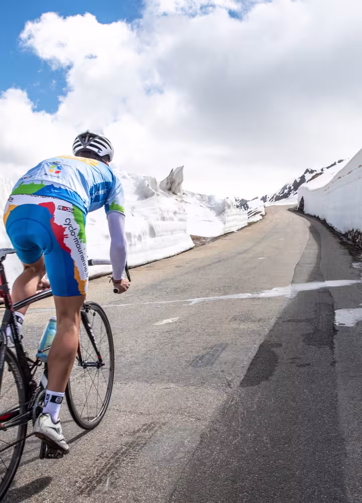 Ciclista nella neve sulla Route des Grandes Alpes
