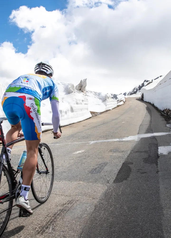 Ciclista nella neve sulla Route des Grandes Alpes