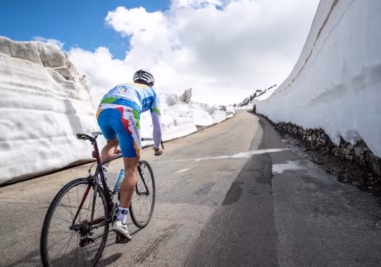 Ciclista nella neve sulla Route des Grandes Alpes