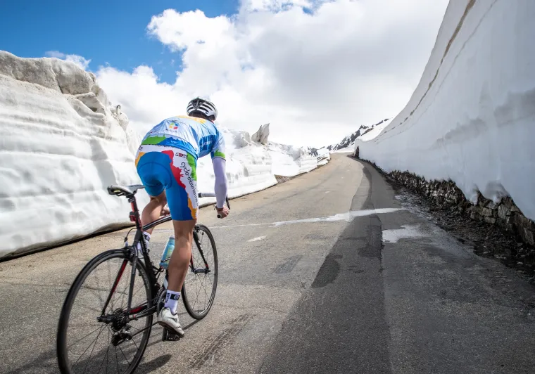 Ciclista nella neve sulla Route des Grandes Alpes